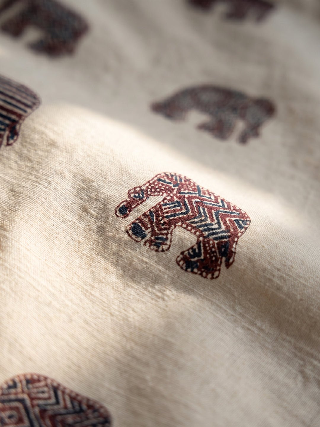 Close-up of a cream-colored fabric with a reddish-brown geometric elephant print