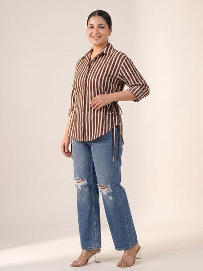 Plus size woman wearing a brown striped button-down shirt and ripped blue denim jeans