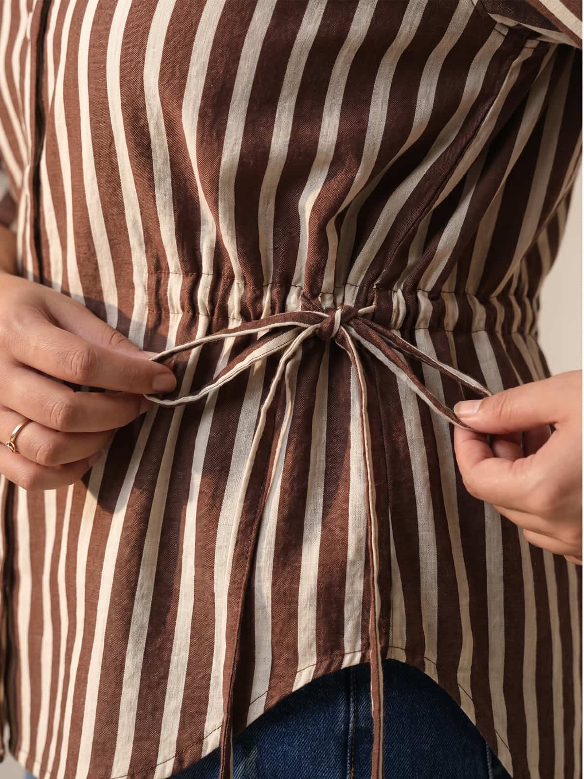 Close-up of a brown and white striped women's shirt with a drawstring waist tie.